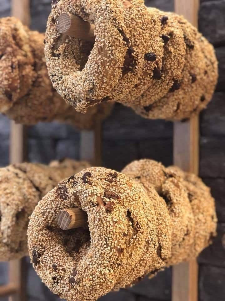 A photo of Thessaloniki's famous koulouria, a sesame seed-covered bread ring with raisins, piled up on a vendor's stall, tempting passersby with its sweet aroma and delicious taste.
